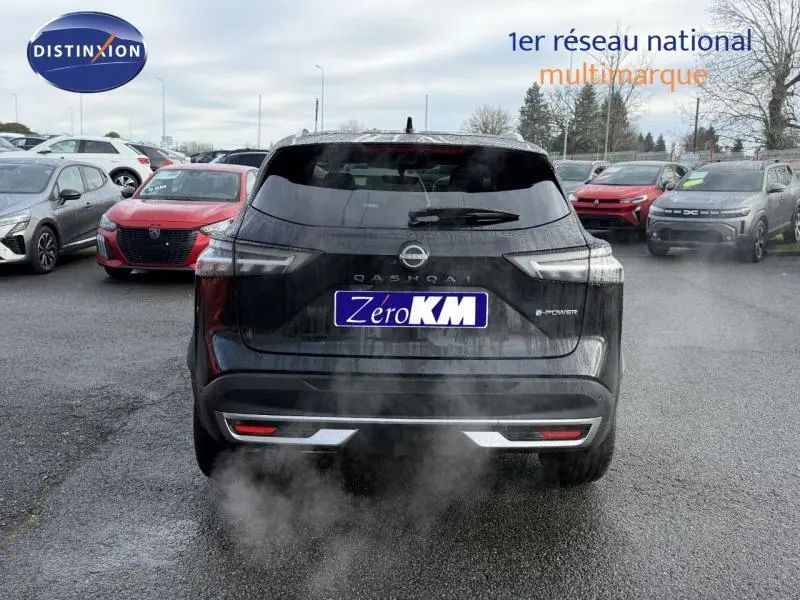 Vue arrière d'un Nissan Qashqai Hybrid e-POWER noir 2025, avec logo et plaque "Zero KM" visible sur un parking.