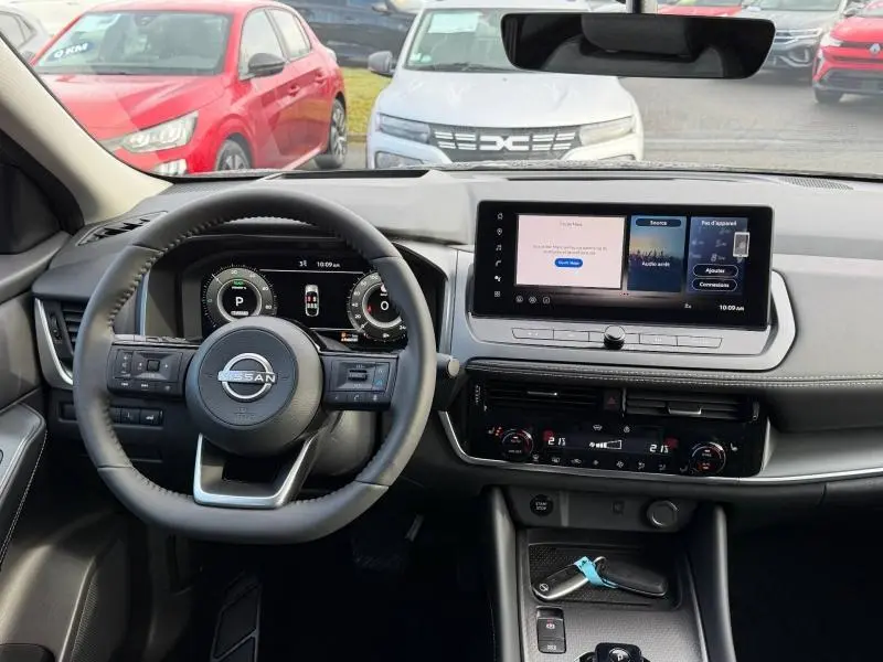 Vue intérieure du tableau de bord du Nissan Qashqai Hybrid e-POWER 2025, avec écran tactile et volant multifonction noir.