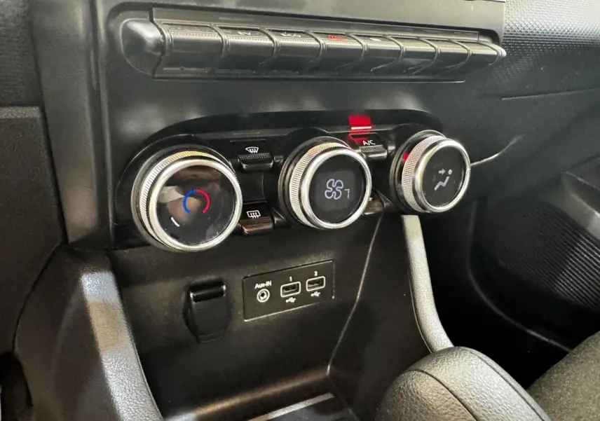 Gros plan sur les commandes de climatisation et les ports USB de la Renault Clio Business E-TECH gris clair.