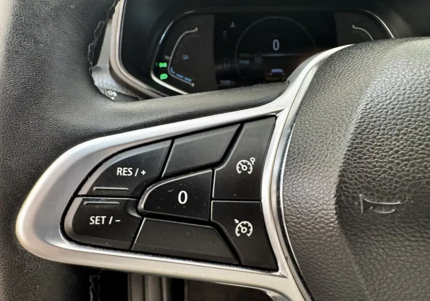 Gros plan sur les commandes du régulateur de vitesse sur le volant cuir noir de la Renault Clio Business E-TECH 140 gris clair.