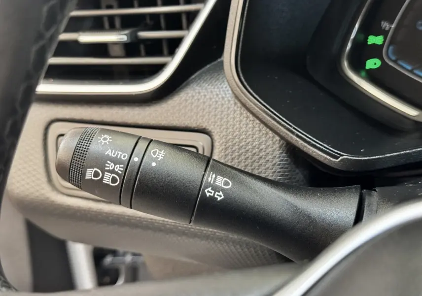 Gros plan sur la commande des phares et clignotants à gauche du volant dans une Renault Clio Business E-TECH 140 gris clair.