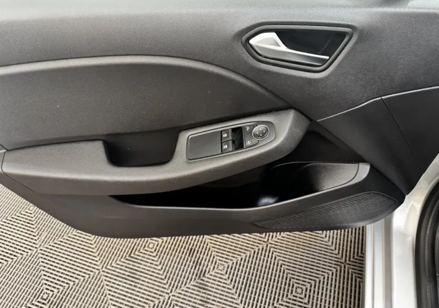 Vue intérieure côté gauche de la porte avant d'une Renault Clio Business E-TECH 140 gris clair avec commandes de vitres et poignée argentée.