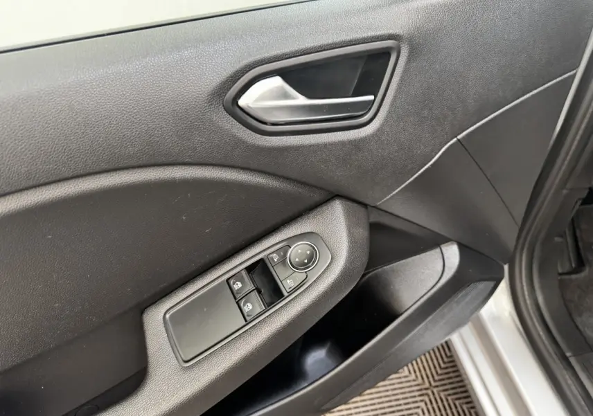 Détail de la porte avant droite grise de Renault Clio Business E-TECH 140 avec commandes électriques des vitres et rétroviseurs.