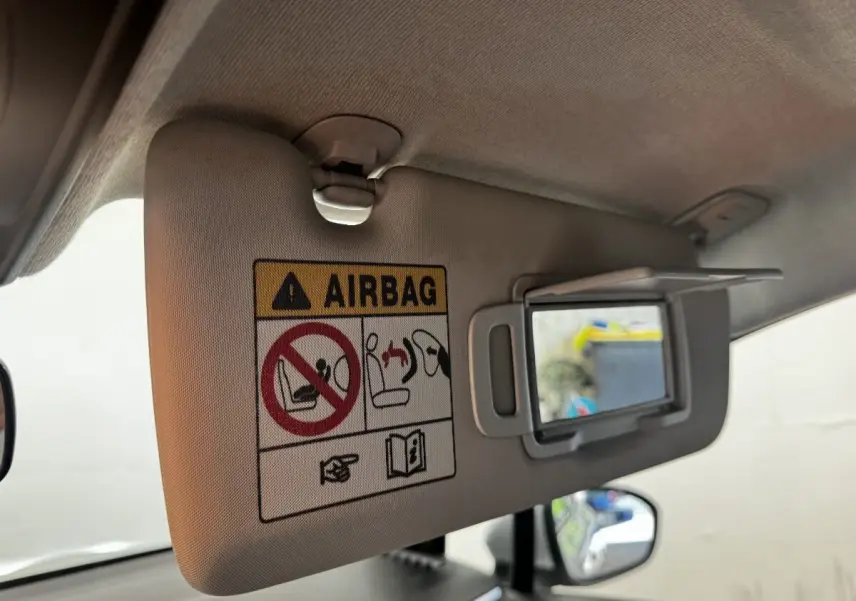Détail du pare-soleil côté conducteur avec miroir de courtoisie ouvert et avertissement airbag dans une Renault Clio gris clair.