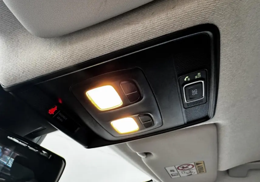Plafonnier intérieur allumé avec commandes SOS et éclairage, vue du toit d'une Renault Clio Business E-TECH gris clair.