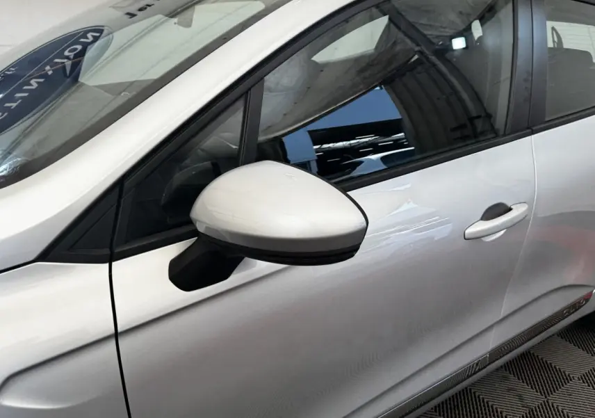 Vue rapprochée du côté gauche de la Renault Clio Business E-TECH 140 gris clair, mettant en valeur le rétroviseur et la portière.