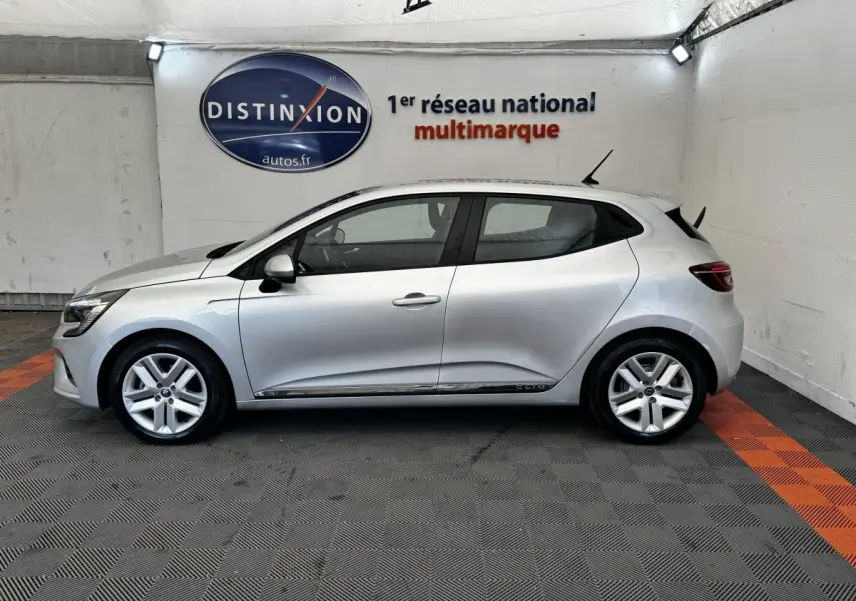 Vue de profil côté gauche d'une Renault Clio Business E-TECH 140 gris clair dans un showroom.