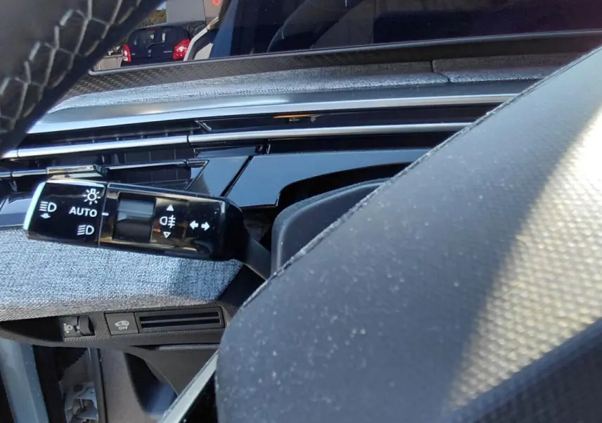 Gros plan sur la commande des feux et clignotants côté gauche du tableau de bord du Peugeot 5008 Hybrid 2025.