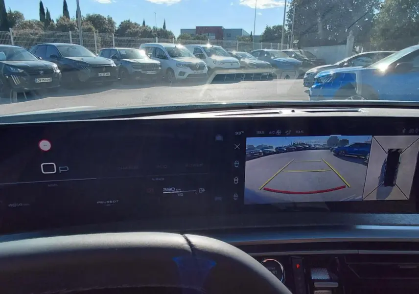 Vue intérieure du tableau de bord du Peugeot 5008 Hybrid blanc 2025, avec écran affichant la caméra de recul et l'affichage numérique.