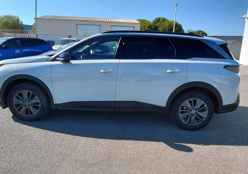 Vue de profil côté gauche du Peugeot 5008 blanc Hybrid 145 ch Allure 2025 garé en extérieur.