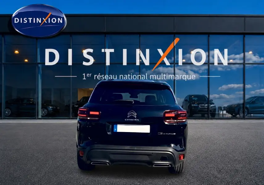 Vue arrière d'un Citroën C5 Aircross noir 2024 garé devant une vitrine avec logo Distinxion.
