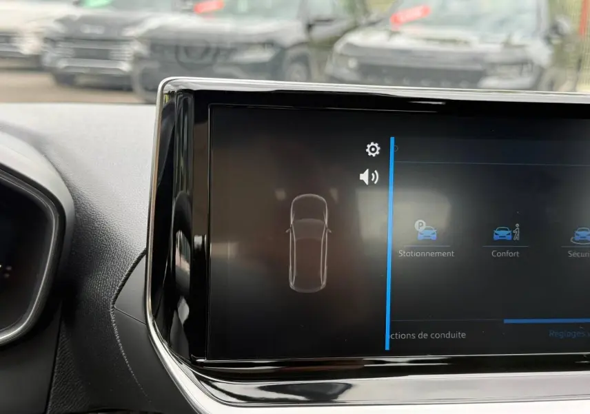 Écran tactile central de la Peugeot 208 2025 montrant les options de stationnement et confort, intérieur noir.