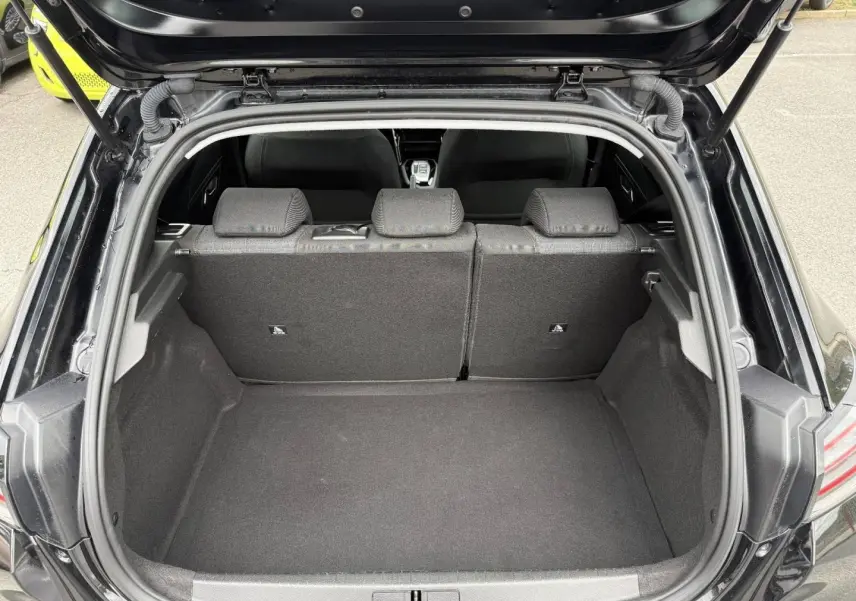 Coffre ouvert vu de l’arrière d’une Peugeot 208 noire Perla Nera avec banquette arrière en tissu gris.