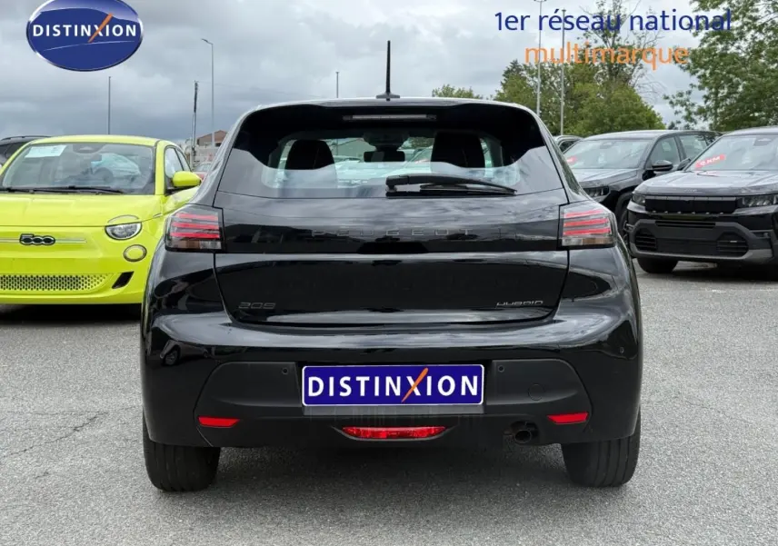 Vue arrière d'une Peugeot 208 noire Perla Nera, avec feux LED et logo distinctif sur un parking multimarques.