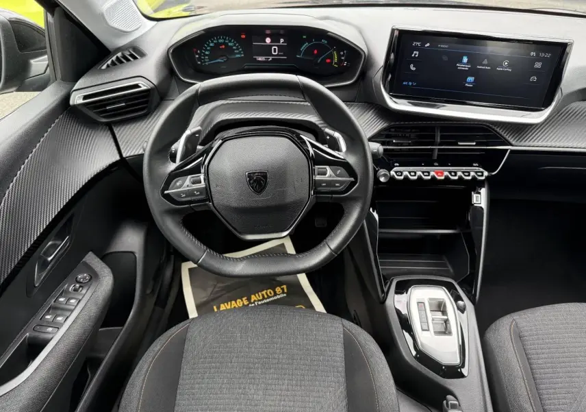Vue intérieure avant du Peugeot 208 1.2 Hybrid 110ch Style 2025, volant cuir, tableau de bord numérique et écran tactile.