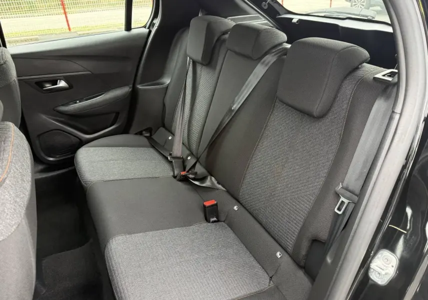 Vue intérieure côté droit des sièges arrière en tissu gris et noir avec surpiqûres orange d’une Peugeot 208 noire Perla Nera.