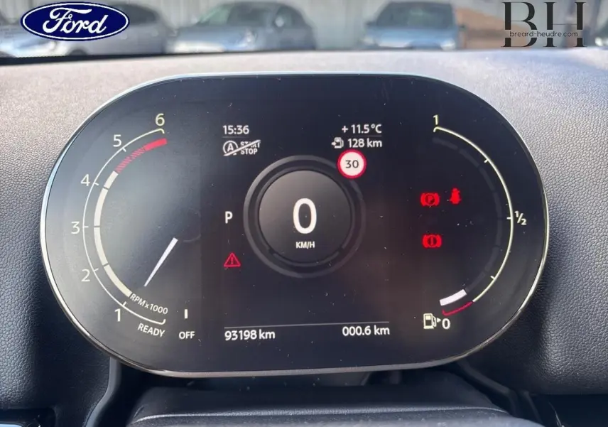 Vue rapprochée du tableau de bord numérique d'une MINI Countryman noire, affichant la vitesse à 0 km/h et divers indicateurs.