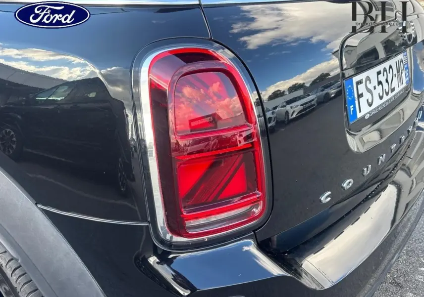 Feu arrière droit et partie arrière en 3/4 d’un MINI Countryman Cooper D noir Midnight avec bandes grises sur capot.