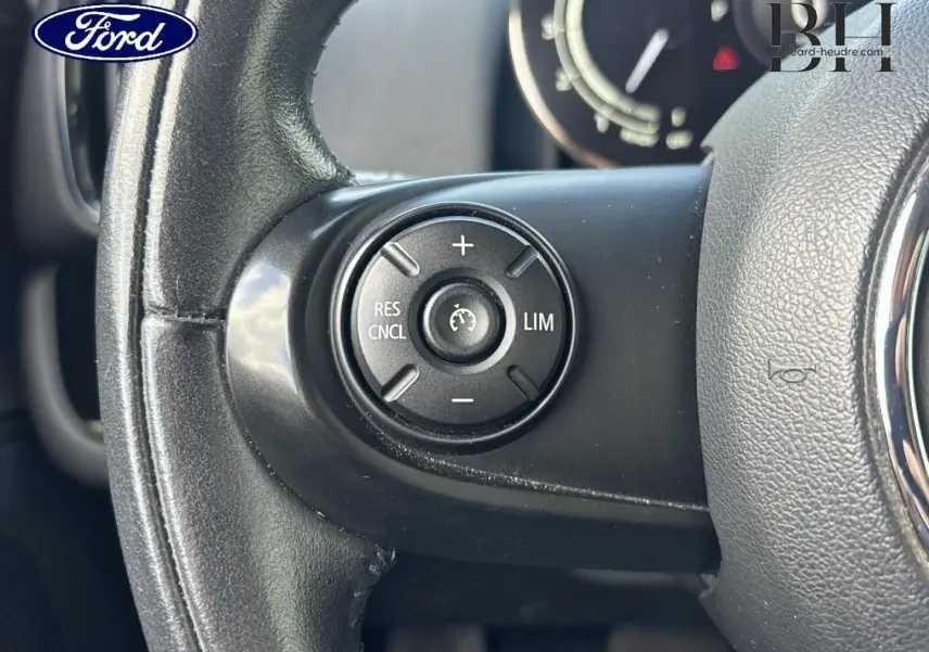 Gros plan sur le volant cuir noir du MINI Countryman Cooper D 2020, avec commandes de régulateur de vitesse visibles.