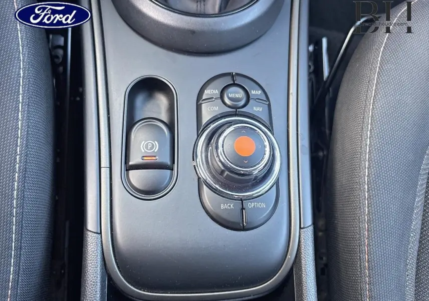 Vue plongeante sur la console centrale noire du MINI Countryman Cooper D 2020 avec commandes multimédia et frein à main électrique.