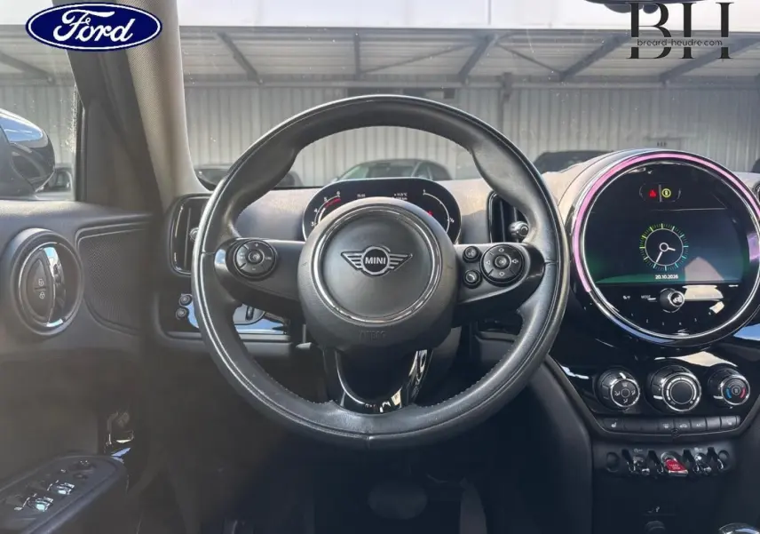 Vue intérieure centrée sur le volant cuir MINI avec tableau de bord et écran tactile rond illuminé.