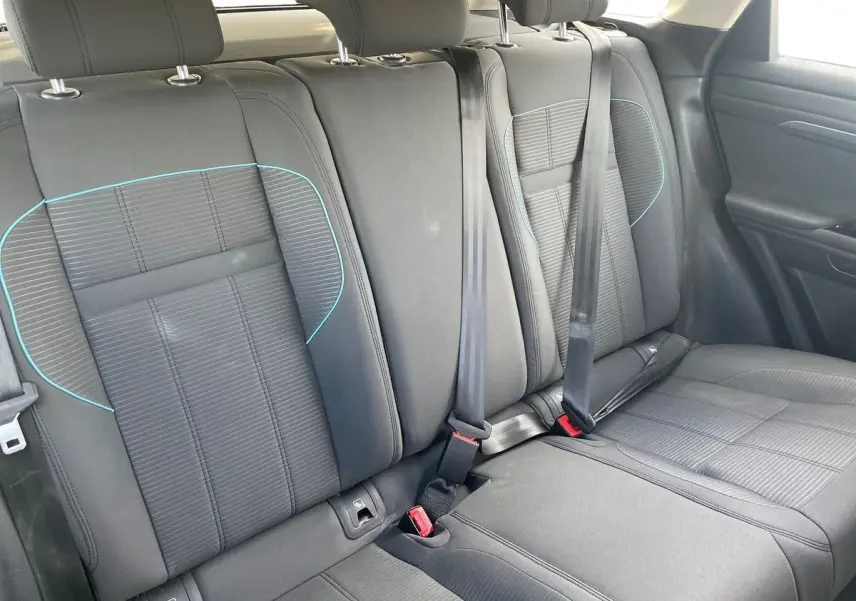 Vue intérieure sur les sièges arrière noirs du Range Rover Evoque 2020 avec surpiqûres bleues et ceintures de sécurité visibles.