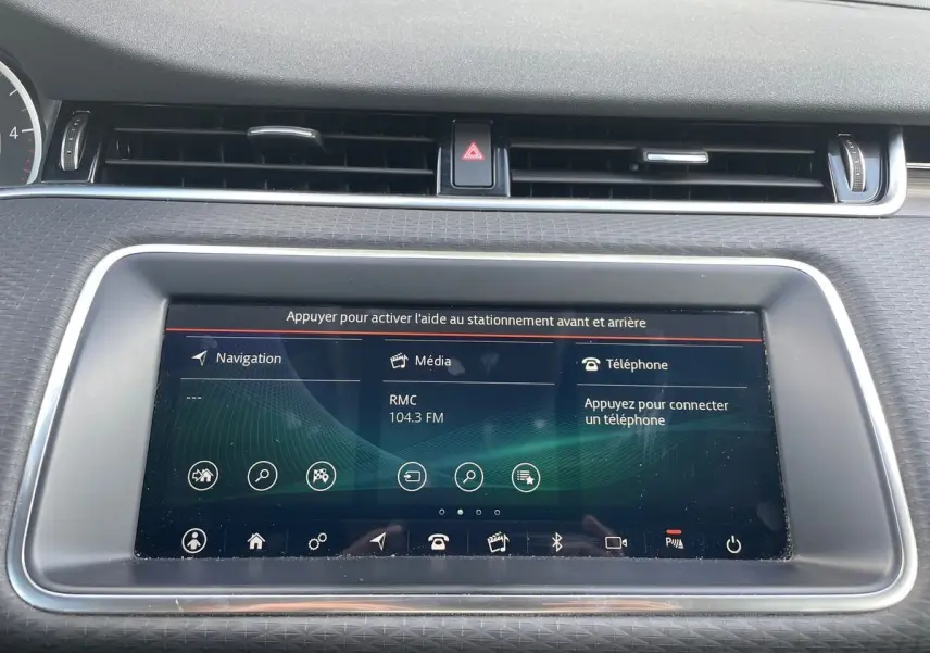 Écran tactile central du tableau de bord du Range Rover Evoque blanc, affichant navigation, média et téléphone.