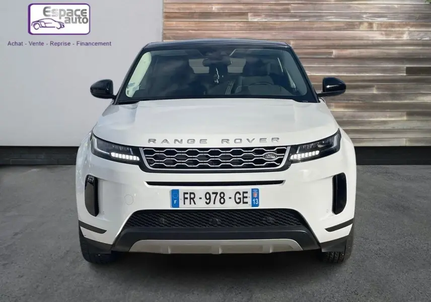 Vue frontale d'un Range Rover Evoque blanc 2020 avec calandre noire et phares LED allumés.