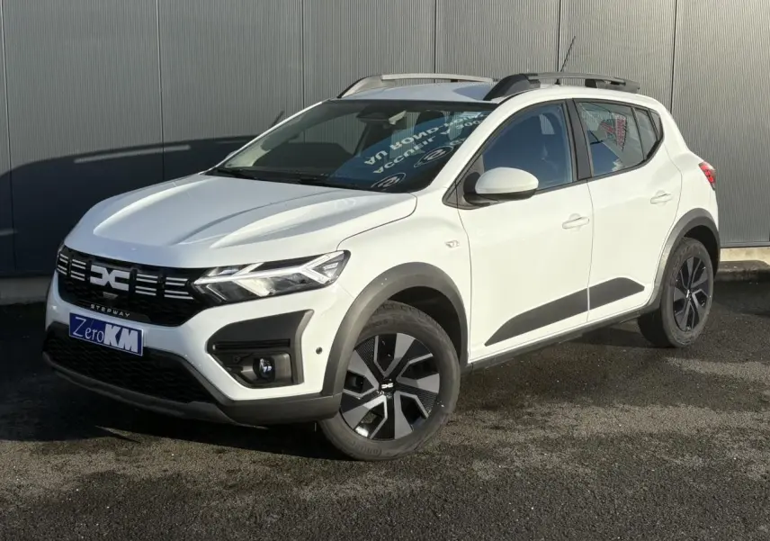 Vue 3/4 avant droite d'une Dacia Sandero Stepway 2024 blanc glacier avec barres de toit et jantes noires.