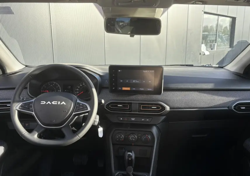 Vue frontale de l’habitacle de la Dacia Sandero Stepway blanc glacier avec tableau de bord et écran tactile central.