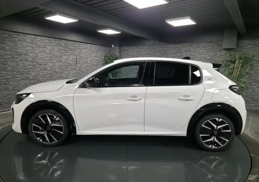 Peugeot 208 GT blanche vue de profil gauche, avec jantes alliage bi-ton et élargisseurs d'ailes noirs brillants.