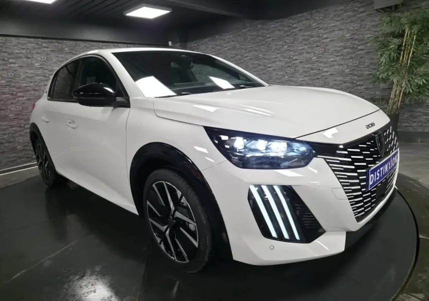 Peugeot 208 blanc banquise en 3/4 avant droit avec calandre noire et feux LED distinctifs allumés.