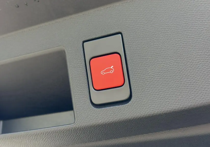Bouton rouge d'ouverture électrique du hayon sur le panneau intérieur d'un Citroën C5 Aircross 2026 gris Platinium.