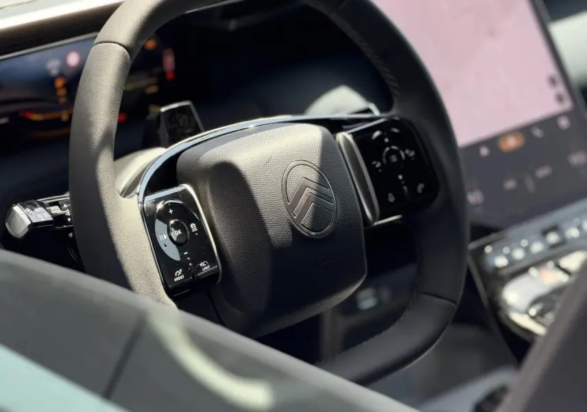 Gros plan sur le volant noir multifonctions Citroën du C5 Aircross 2026 avec écran tactile en arrière-plan flou.