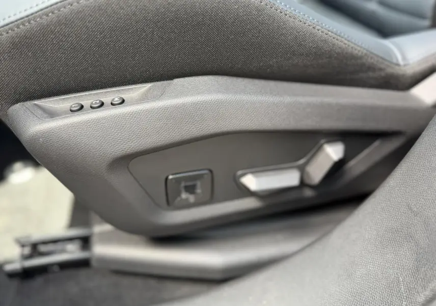 Détail des commandes électriques de réglage du siège conducteur en tissu gris dans une Citroën C5 Aircross.