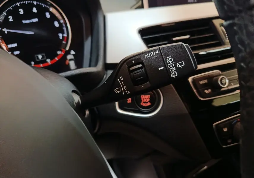 Gros plan sur la commande d’essuie-glace à gauche du volant cuir dans l’habitacle du BMW X1 gris foncé 2021.