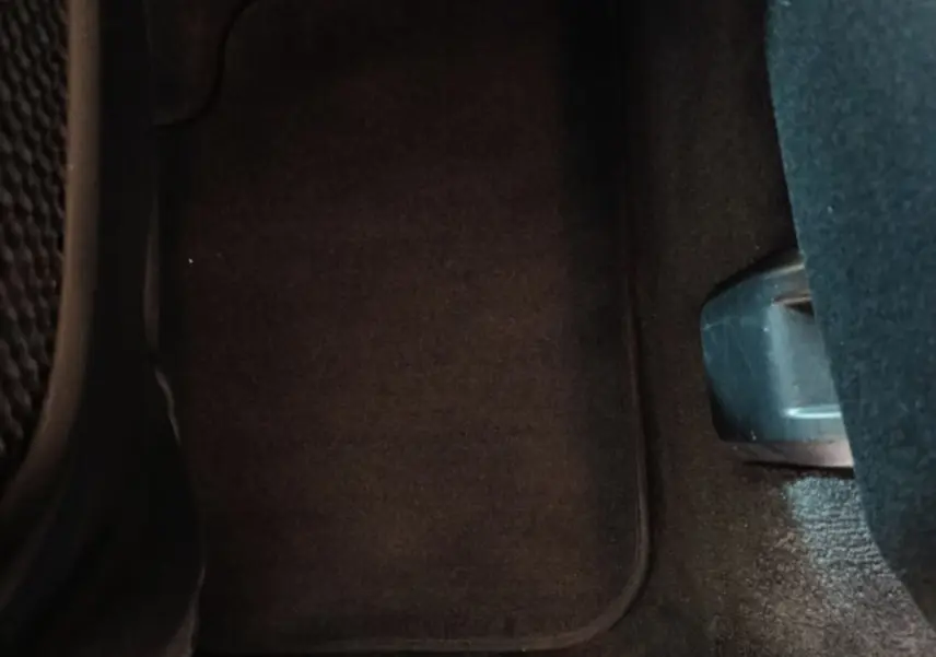 Vue rapprochée du tapis de sol noir côté passager arrière d'un BMW X1 sDrive18i Lounge gris foncé.