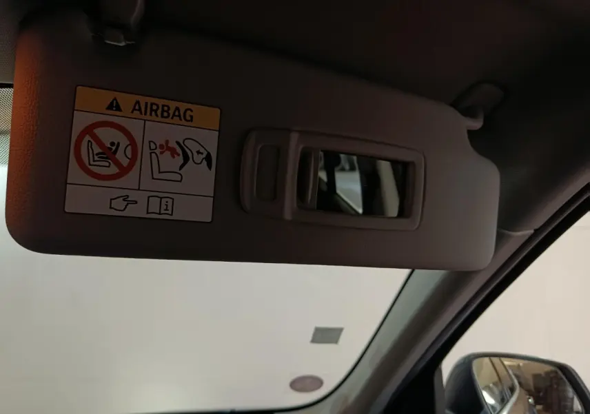 Détail du pare-soleil côté conducteur avec miroir et avertissement airbag dans un BMW X1 gris foncé 2021.