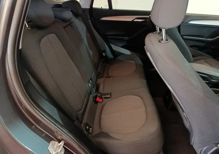 Vue intérieure côté gauche montrant la banquette arrière grise du BMW X1 sDrive18i Lounge 2021 avec sièges tissu.