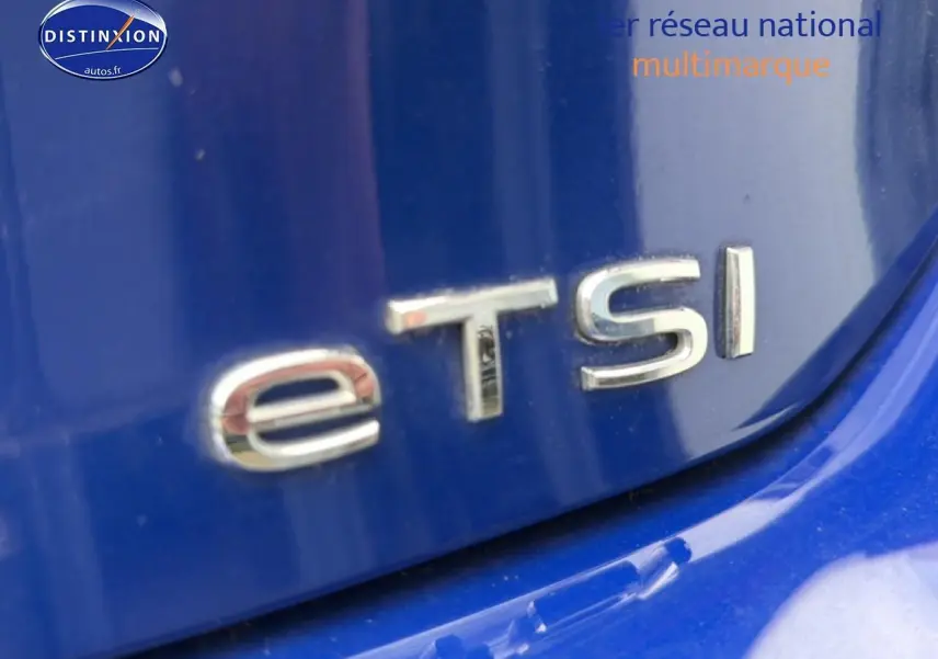 Gros plan sur le badge "eTSI" argenté sur la carrosserie bleue d'une Volkswagen Golf 2024.