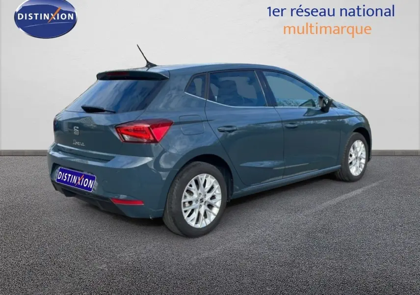 Vue 3/4 arrière droite d'une SEAT Ibiza bleu fjord avec jantes alliage et vitres teintées sur parking.