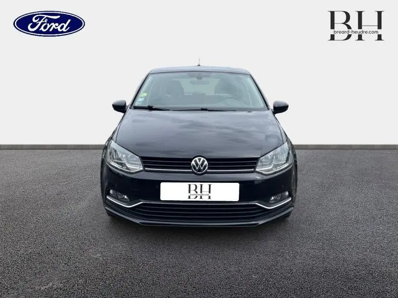 Vue frontale d'une Volkswagen Polo noire unie de 2017 avec calandre chromée et phares halogènes allumés.