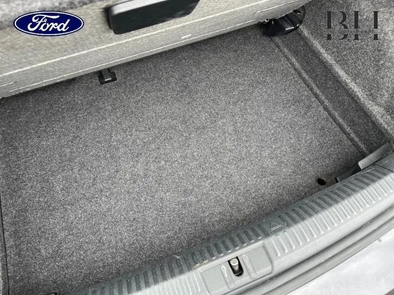 Coffre vide vu de dessus d'une Volkswagen Polo noire, montrant la moquette grise et les finitions intérieures.