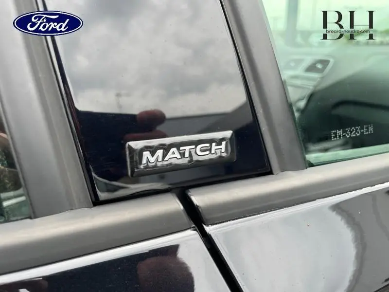 Gros plan sur l'écusson Match sur la porte arrière droite d'une Volkswagen Polo noire unie.