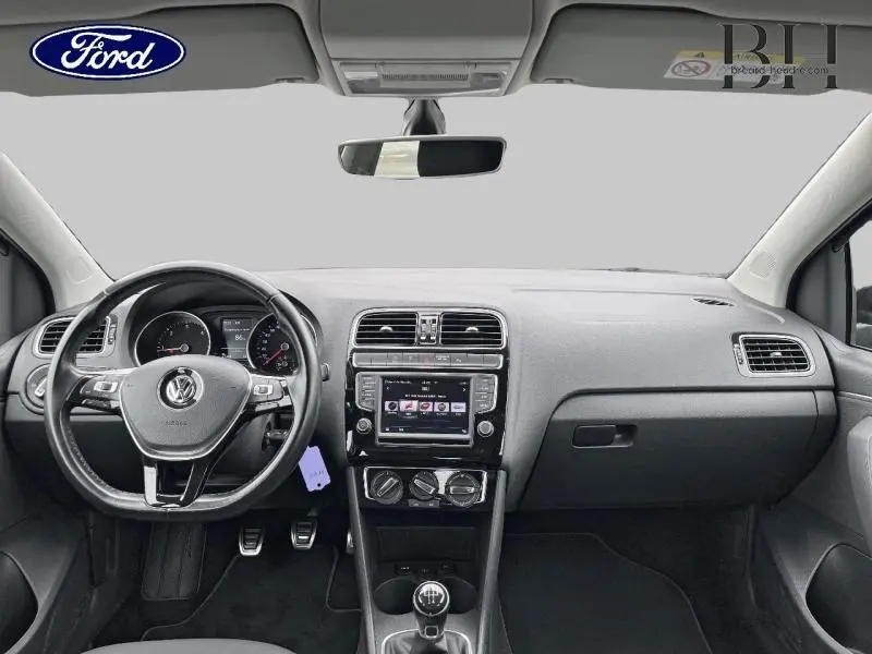 Vue intérieure frontale du tableau de bord noir d'une Volkswagen Polo 2017 avec volant cuir multifonction et écran tactile central.