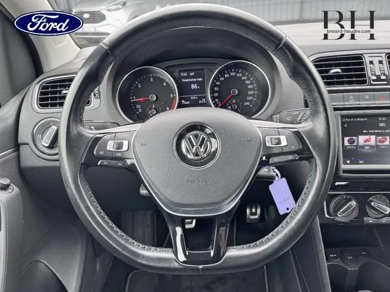 Vue centrée sur le volant cuir noir et le tableau de bord d'une Volkswagen Polo 2017 avec écran tactile et compteurs analogiques.