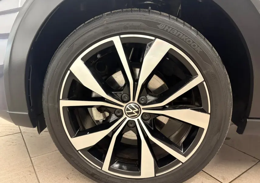 Gros plan sur la jante alliage noir et argentée 18 pouces du Volkswagen Taigo gris cendré, avec logo VW central.