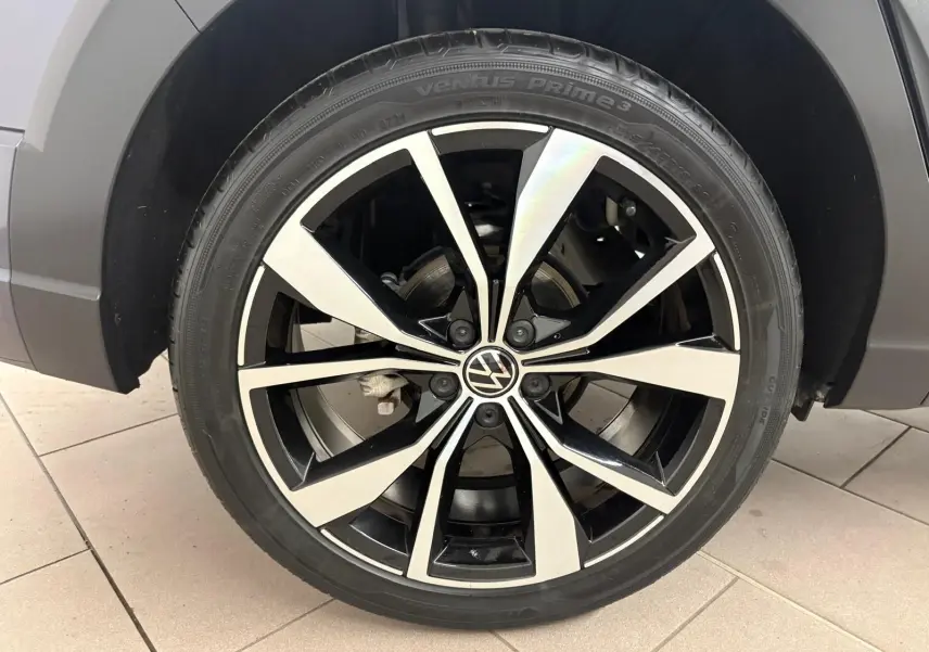 Gros plan sur la jante alliage noir et argent 18 pouces du Volkswagen Taigo gris cendré, détail du pneu et logo VW au centre.