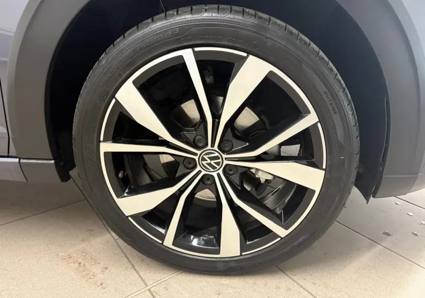 Gros plan sur la jante alliage noir et argent 18 pouces du Volkswagen Taigo gris cendré, avec logo VW central.