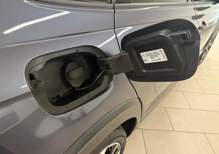 Gros plan sur la trappe à carburant ouverte côté gauche d’un Volkswagen Taigo gris cendré 2024.